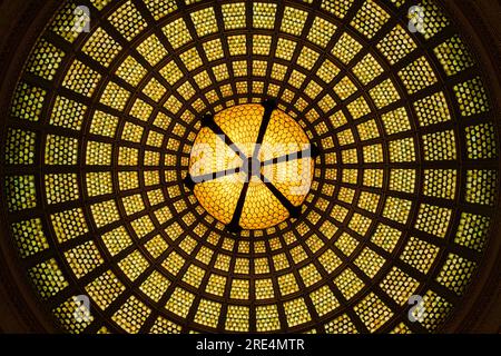 Vue en perspective unique d'un plafond en dôme en verre Tiffany, centré par un lustre en verre Tiffany suspendu au dôme lui-même. Situé dans le Preston Bradley Hall de l'historique Chicago Cultural Center. Photo prise en regardant du centre de la majestueuse salle. Banque D'Images