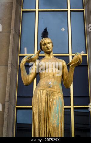 Statue féminine peinte en or avec des pigeons et un vrai pigeon sur le dessus de sa tête devant le Palais de Chaillot (Trocadéro), Paris, France Banque D'Images