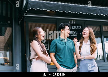 Asian hommes et femmes amis Bonding sur la rue en face de Cozy café. Jeunes amis adultes qui parlent et passent un bon moment ensemble. Concept Youthful Urban Lifestyle Banque D'Images