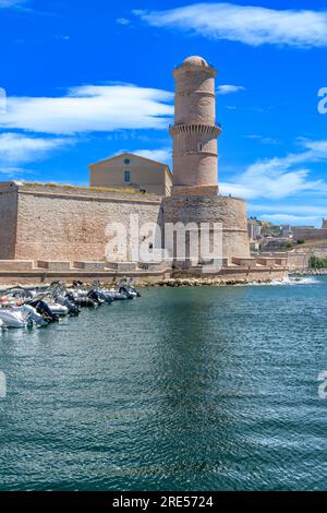 Des rangées de hors-bord amarrées ferment la ville de Marseille. Derrière se trouve la tour de pierre de la Tour du Fanal, construite en 1644 pour guider les navires dans le vieux port. Banque D'Images