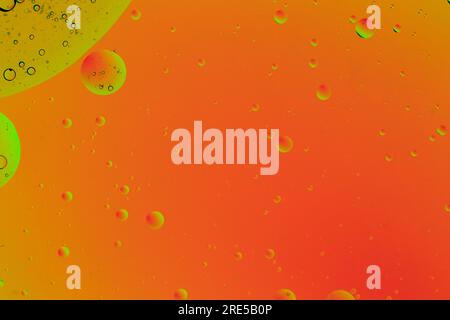 Fond orange abstrait avec des bulles jaunes en haut à gauche. Cercles organiques parfaits faits avec de l'huile dans l'eau. Simulation d'un système cellulaire et d'une image spatiale Banque D'Images