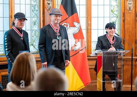 Hanovre, Allemagne. 25 juillet 2023. Klaus Meine (à droite), chanteur du groupe de rock 'Scorpionss', parle après avoir reçu la Grand Croix du mérite de l'ordre du mérite de Basse-Saxe dans la maison d'hôtes du gouvernement de l'État. A côté d'eux se trouvent Matthias Jabs (l) et Rudolf Schenker (2e à partir de la gauche), tous deux membres du groupe The Scorpion. Trois membres du groupe rock 'Scorpions' sont honorés pour leur musique ainsi que pour leur engagement honorifique en Basse-Saxe. Crédit : Michael Matthey/dpa/Alamy Live News Banque D'Images