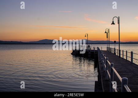 Lac avec jetée au coucher du soleil. Paysage italien relaxant au coucher du soleil en automne. Lac Trasimeno au coucher du soleil Banque D'Images