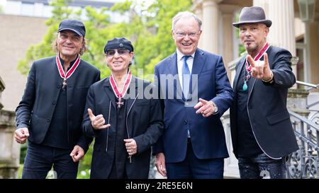 Hanovre, Allemagne. 25 juillet 2023. Matthias Jabs (de gauche à droite), membre du groupe "Scorpion", Klaus Meine, membre du groupe "Scorpion", Stephan Weil (SPD), ministre-président de Basse-Saxe, Et Rudolf Schenker, membre du groupe des 'Scorpions', se tiennent dans le jardin de la maison d'hôtes du gouvernement de l'État après avoir reçu la Grand Croix du mérite de l'ordre du mérite de Basse-Saxe. Trois membres du groupe rock 'Scorpions' sont honorés pour leur musique ainsi que pour leur engagement honorifique en Basse-Saxe. Crédit : Michael Matthey/dpa/Alamy Live News Banque D'Images