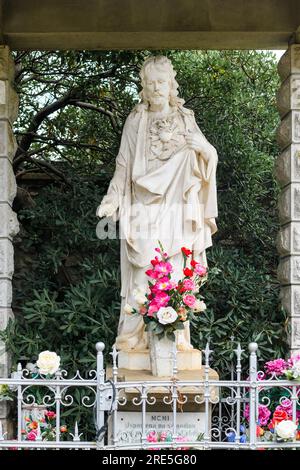 Crikvenica, Croatie - 21 juillet 2023 : statue de Jésus-Christ au cimetière local avec des bougies et des fleurs Banque D'Images