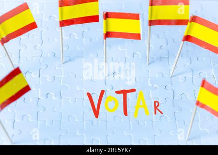 Élections en Espagne, concept de drapeau espagnol et lettrage VOTAR signifiant vote en anglais sur des pièces de puzzle blanches Banque D'Images