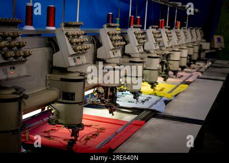 Machines de broderie automatiques dans une usine textile au Guatemala travaillant sur des tissus colorés Banque D'Images
