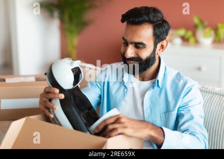 Joyeux acheteur du Moyen-Orient déballant l'appareil livré à la maison Banque D'Images