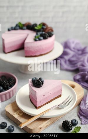 Gâteau aux myrtilles ombrées. Délicieux dessert estival décoré de myrtilles fraîches, mûres, biscuits au chocolat et feuilles de menthe. Couleur violette. Banque D'Images