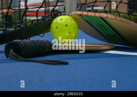 Gros plan de deux palettes de pickleball et balles de fouet sous un filet sur un court de pickleball de tennis. Banque D'Images