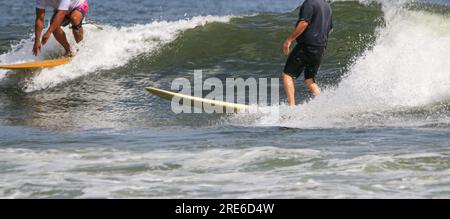 Deux hommes attrapent la même vague sur des planches de surf à Gilgo Beach sur long Island. Banque D'Images