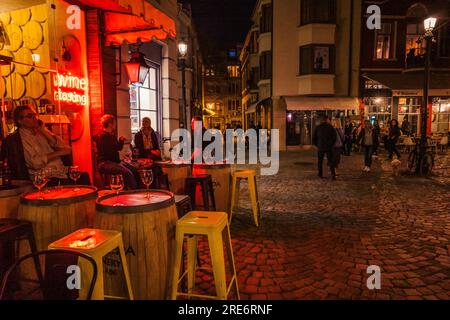 Tabourets, une table et un signe au néon rayonnant sur des pavés devant un bar à vin à Plovdiv, Bulgarie Banque D'Images