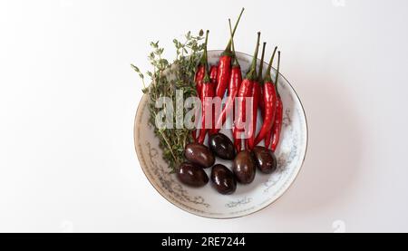 Olives, piments Chili et thym dans une petite assiette ronde Banque D'Images