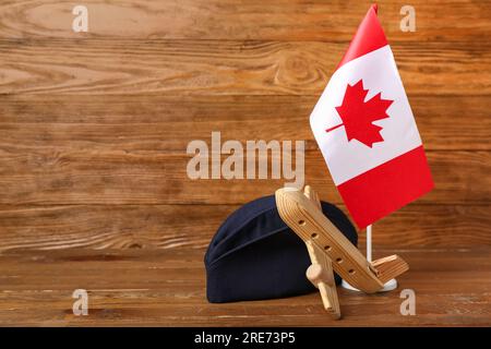 Drapeau du Canada avec chapeau d'hôtesse et jouet d'avion sur fond de bois Banque D'Images