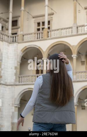 Une femme voyageur dans des lieux historiques regarde autour de la cour d'un monument dans le château de Krakow Wawel. Tourisme dans un lieu historique le jour ensoleillé. Femme Tourisme et blogging partage en direct en ligne pour le voyage de l'auditoire ensemble Banque D'Images