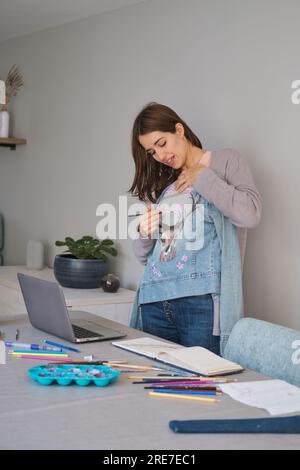 Femme caucasienne en streaming montrant son design d'art dans une veste en denim. Banque D'Images