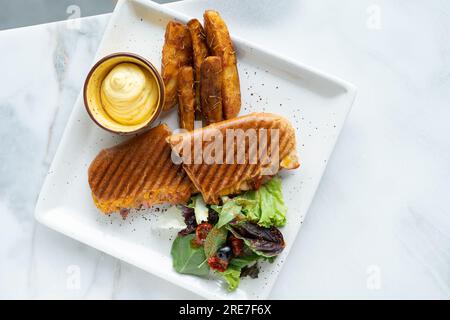 Sandwich panini Burger. Pommes de terre frites avec salade et trempette. Vue de dessus d'arrière-plan floue Banque D'Images