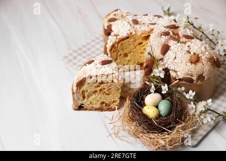 Délicieux gâteau italien de colombe de Pâques (Colomba di Pasqua traditionnel), nid décoratif avec des œufs peints et des branches fleuries sur la table blanche. Espace pour Banque D'Images