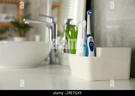 Brosses à dents électriques et tube de pâte sur comptoir blanc dans la salle de bain. Espace pour le texte Banque D'Images