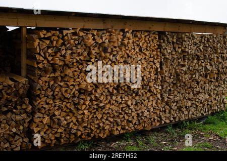 Beaucoup de bois de chauffage empilés coupés dans l'entrepôt extérieur Banque D'Images