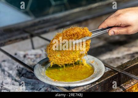 Dessert turc kunefe, kunafa, kadayif avec poudre de pistache et fromage, servi chaud, très sucré. Dessert traditionnel turc sur fond de bois Banque D'Images