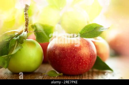 Pommes fraîches rouges et vertes avec des feuilles sur la table en bois Banque D'Images