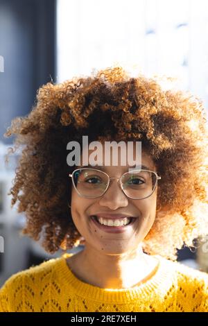 Portrait d'heureuse femme d'affaires occasionnelle biracial avec les cheveux bouclés sur le modèle de bâtiment dans le bureau Banque D'Images