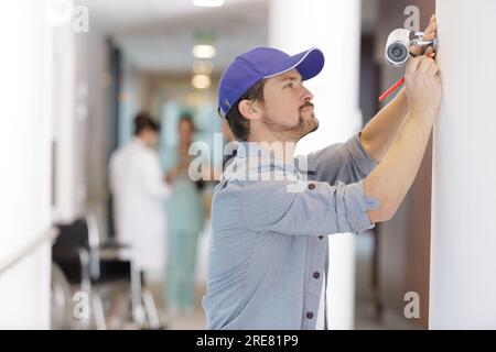 homme installer caméra de surveillance pour la maison Banque D'Images