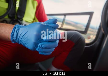 Gros plan des mains du médecin dans des gants chirurgicaux à l'intérieur de l'hélicoptère du service médical d'urgence. Thèmes sauvetage, aide et espoir. Banque D'Images
