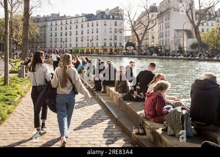 Des foules de gens traînent le long du canal dans le quartier prometteur du Canal Saint Martin à Paris, par une belle journée de printemps. Banque D'Images