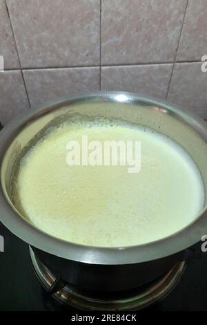 Vue du lait bouillant dans un récipient en acier inoxydable conservé sur la cuisinière à gaz Banque D'Images