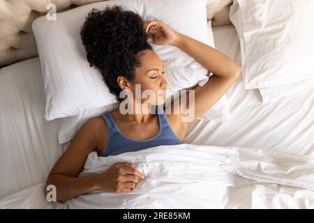 Femme biracial dormant dans le lit dans la chambre Banque D'Images