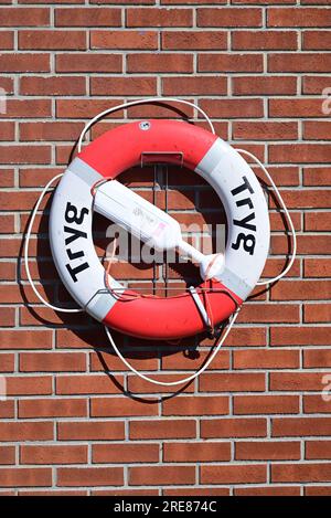 Bouée de sauvetage sur un mur de briques dans un port norvégien. Banque D'Images