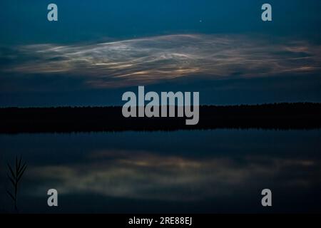 Nuages Noctilucent, ou nuages brillants de nuit dans le reflet de l'eau du lac. Banque D'Images