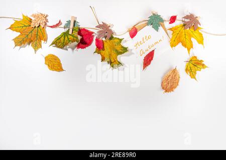 Composition créative de bordure de cadre d'automne avec feuilles d'automne. Les feuilles d'automne rouges et jaunes pendent sur corde à linge, sur fond blanc espace de copie pour t Banque D'Images