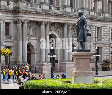 Étudiants MLA (Move Languages Ahead) et autres piétons devant Glasgow City Chambers à George Square dans le centre-ville. La statue de James Oswa Banque D'Images