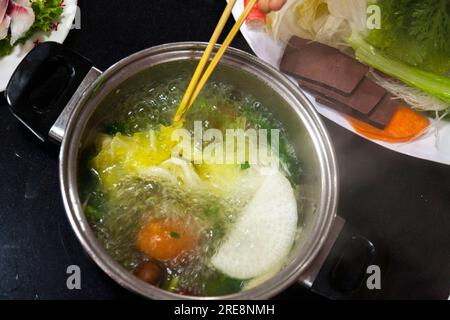 Repas de légumes bouillis dans un café hot pot, y compris faire bouillir des feuilles chinoises / cuisson du chou chinois à manger par un jeune couple. Pékin RPC. Chine. (125) Banque D'Images