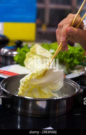 Repas de légumes bouillis dans un café hot pot, y compris faire bouillir des feuilles chinoises / cuisson du chou chinois à manger par un jeune couple. Pékin RPC. Chine. (125) Banque D'Images