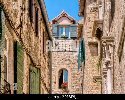 Étages supérieurs de bâtiments résidentiels médiévaux en pierre, avec fenêtres pittoresques à volets et jardinières, dans une ruelle étroite, à Split, Croatie. Banque D'Images