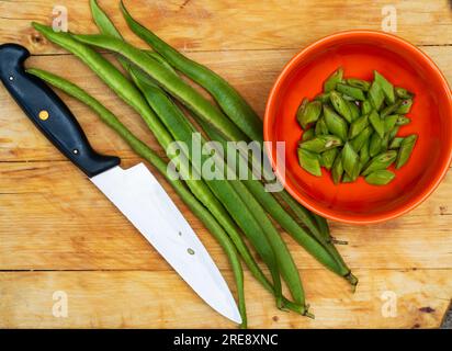 Haricot de coureur cultivé maison, Phaseolus coccineus 'Enorma' tranché et non tranché sur une planche à découper Banque D'Images