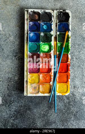 Vue de dessus de la palette de peintures aquarelle colorées lumineuses utilisées sur fond gris Banque D'Images