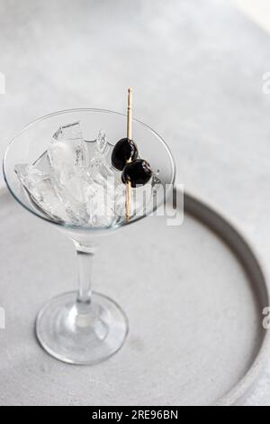 D'en haut verre rempli d'alcool cocktail de vodka martini avec des olives noires en verre martini sur la table en béton Banque D'Images