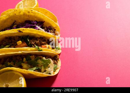 Vue à angle élevé des tacos avec des tranches de citron sur fond rose, espace de copie Banque D'Images