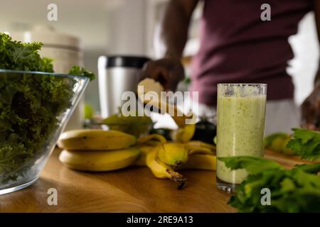Section médiane de l'homme afro-américain préparant un smoothie sain dans la cuisine à la maison Banque D'Images