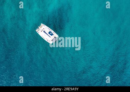 Vue aérienne d'un yacht à voile ancré dans la mer émeraude. Vue aérienne d'un bateau. Sports nautiques en plein air, yachting. Vue aérienne du yacht d'ancrage en plein air Banque D'Images