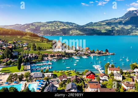 Vue sur l'église et la ville de Spiez sur les rives du lac Thun dans le canton suisse de Berne au coucher du soleil, Spiez, Suisse. Ville de Spiez sur le lac Thun dans le déc Banque D'Images