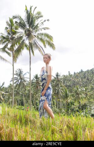 Portrait de mode en plein air de jeune femme dans le champ de riz sur l'île tropicale avec de beaux cocotiers palmiers, lumière naturelle du soleil. Concept de freedo Banque D'Images