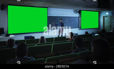 Jeune professeur d'université expliquant une conférence, pointant sur une maquette d'écran vert. Groupe de divers étudiants multiethniques Banque D'Images