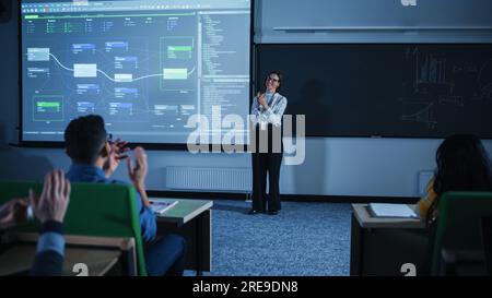 Jeune enseignante féminine donnant une conférence sur la science des données à divers groupes multiethniques d'étudiants féminins et masculins dans Dark College Room. Projection du diaporama Banque D'Images