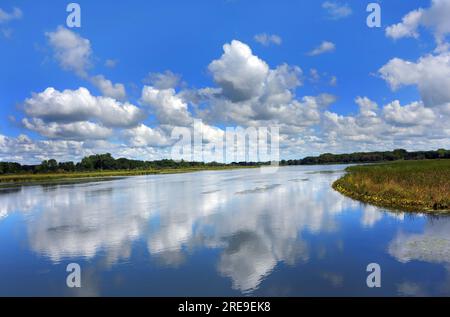 La vue depuis le sentier de la rivière Yahara, est lisse comme le verre. La réflexion du ciel et des nuages transforme l'eau en bleu. Banque D'Images